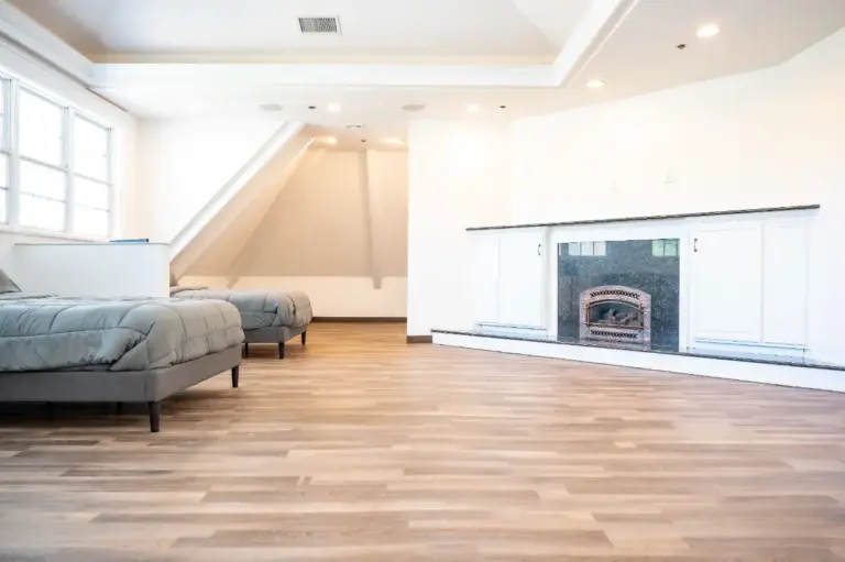 Spacious bedroom at Shore Point Recovery Center with two beds, hardwood floors, and fireplace