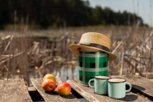 A calming outdoor scene featuring fresh apples and two enamel mugs on a rustic wooden table near a peaceful lakeside. This image represents the importance of balanced food in recovery, highlighting simple, nourishing choices that support physical healing and emotional well-being.